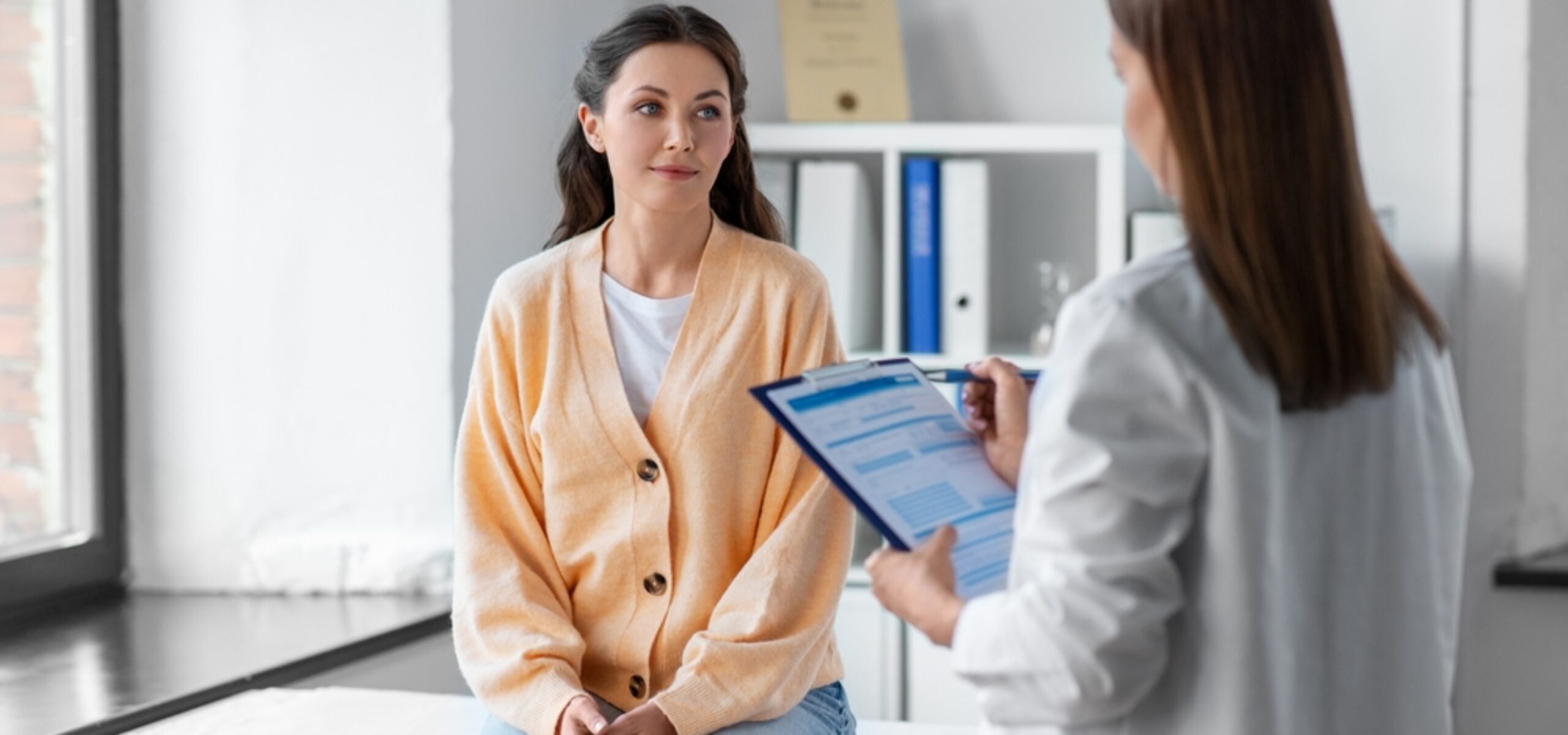 medicine, healthcare and people concept - female doctor with clipboard talking to woman patient at hospital